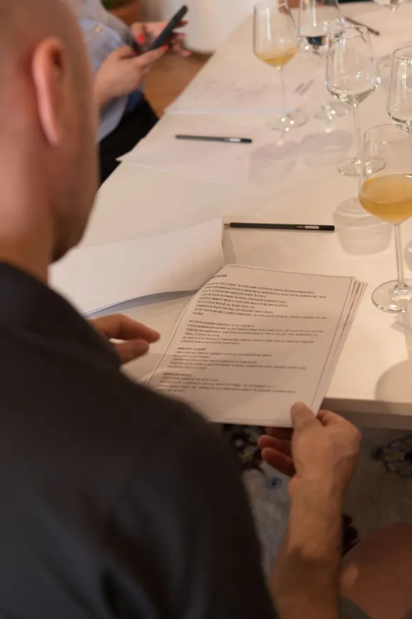 Un participant citind pagina despre îmbuteliere și a doua fermentație din ghidul workshopului